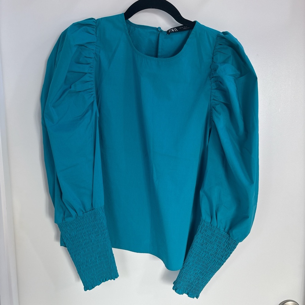Turquoise blouse with puffy arms.